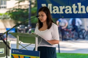 Student reads from podium in front of library 